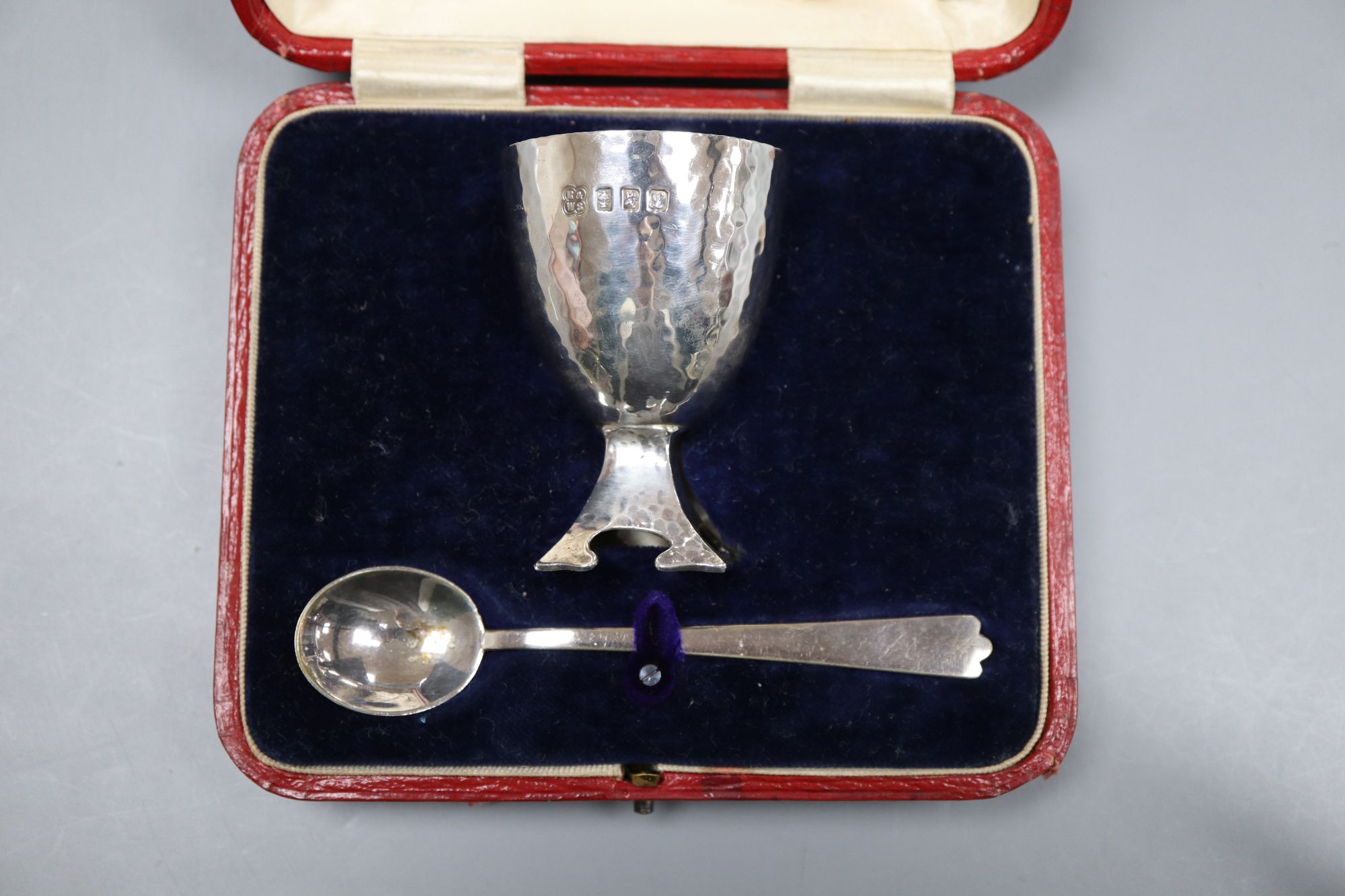 A cased Edwardian Art Nouveau silver egg cup and similar plated egg spoon, R & W Sorley, Glasgow, 1908, 67mm, 55 grams,